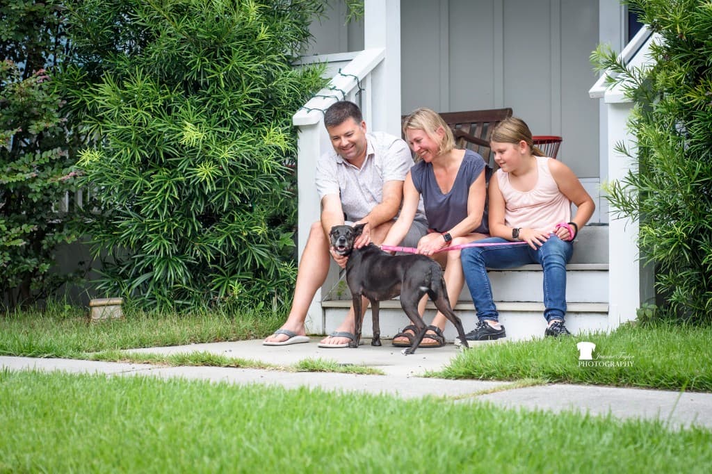 A family sitting on their front porch with their adopted rescue dog